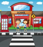 Dos estudiantes cruzando la calle frente a la escuela. vector