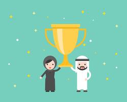 Empresario árabe y mujer árabe con gran trofeo de oro.