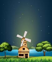 A wooden barnhouse at the river with a windmill vector