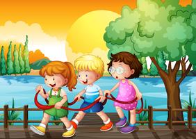 Three kids playing inside the ribbon at the wooden bridge vector