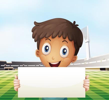 A smiling boy holding an empty signage at the soccer field