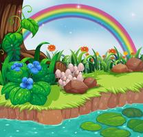 A riverbank with flowers and a rainbow vector