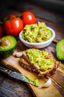 Guacamaole with bread and avocado on rustic wooden background
