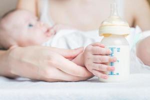 bebé sosteniendo un biberón con leche materna foto