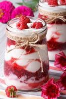 raspberry dessert in a jar and flower on table, vertical photo