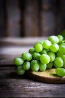Vine of green grapes on rustic wooden background photo