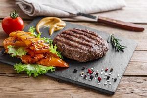 burger grill with vegetables and sauce on a wooden surface photo