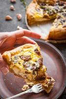 Woman's hand holding a caramelized garlic tart with goat cheese