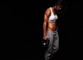 mujer muscular haciendo ejercicio de gimnasio con campana hervidor de agua