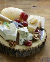 tabla de quesos con quesos variados (parmesano, brie, azul, cheddar)