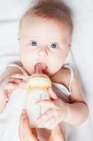 simpático bebé sosteniendo una botella con leche materna foto