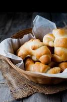 Rollos de mantequilla pan en cesta de mimbre contra el fondo rústico oscuro foto