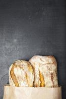 Bolsa de papel de pan francés fresco sobre un fondo oscuro foto