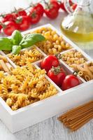 various raw wholegrain pasta in white wooden box photo