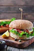 burger with pickled salmon, lettuce, white onion and capers