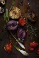cebollas asadas y verduras en tabla de cortar foto