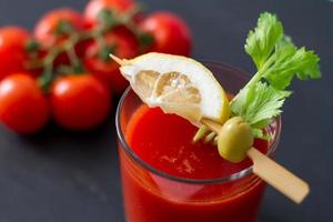 Tomatoes in glass with olive and lemon and stick photo