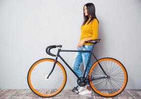 mujer sonriente de pie cerca de bicicleta