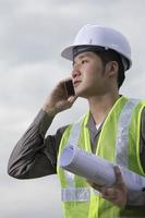 Ingeniero industrial asiático en el trabajo mediante teléfono.