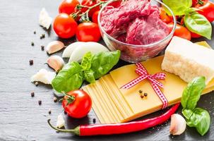 ingredientes de lasaña: láminas secas, carne, tomates cherry, queso, foto