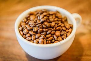 Coffee beans in cup on grunge wooden background