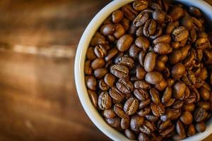 Coffee beans in cup on grunge wooden background