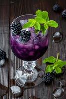 Blackberry cocktail in wine glass with mint and ice photo