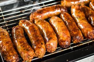 Fresh sausage and hot dogs grilling outdoors photo