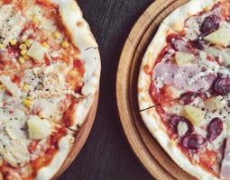 Two delicious pizzas with pineapple and meat photo