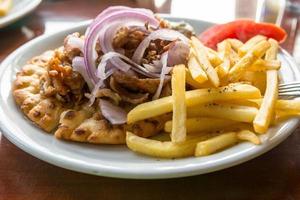 Lamb gyros with onion of fries.