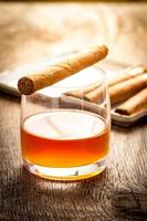 Cuban cigars on wooden table with glass of rum photo