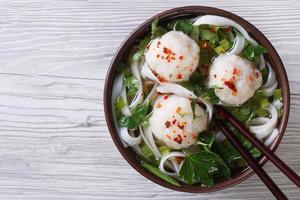 Sopa asiática con bolas de pescado y fideos de arroz vista superior foto