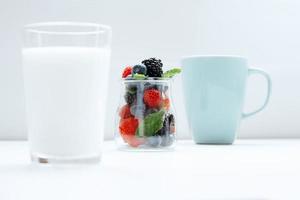 Parallax Berries in transparent jar between glass of milk