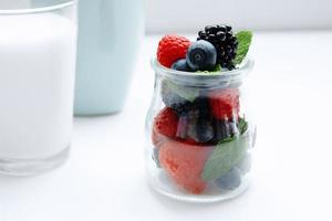 berries and mint in jar and glass of milk photo
