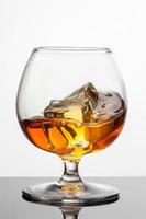 Splash de whisky con hielo en vidrio aislado en blanco foto