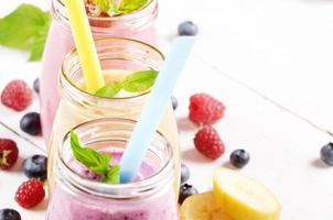 Assorted fruit shakes on white table photo