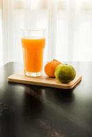 Glass of freshly pressed orange juice with two orange