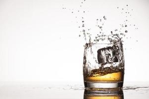 Ice splash into whiskey or brandy