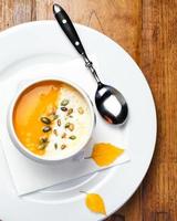 Pumpkin soup with cream and seeds in a white bowl