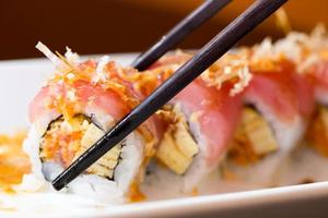 Sushi roll with black chopsticks photo