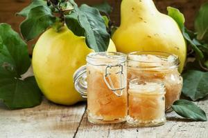 Pink quince jam in glass jars and fresh quince photo