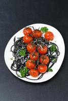 plato de pasta negra con tomates al horno, queso parmesano