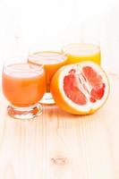 Three glasses of juice with cut in half grapefruit photo