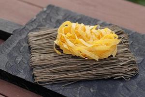 Two types of pasta on wooden plank
