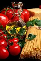 Pasta raw isolated on black tomatoes,olive oil,garlic verti photo