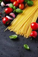 Uncooked spaghetti with tomato and basil