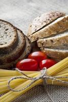 Dry pasta and tomatoes with sliced bread on sack background