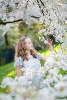 hermosa niña en el jardín de los cerezos en flor foto