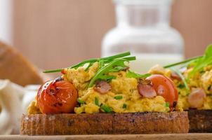 Scrambled eggs witch bacon, herbs and tomato photo