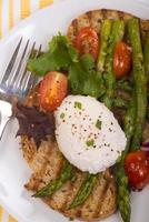 Poached egg on toasted bread with asparagus, tomatoes and greens photo
